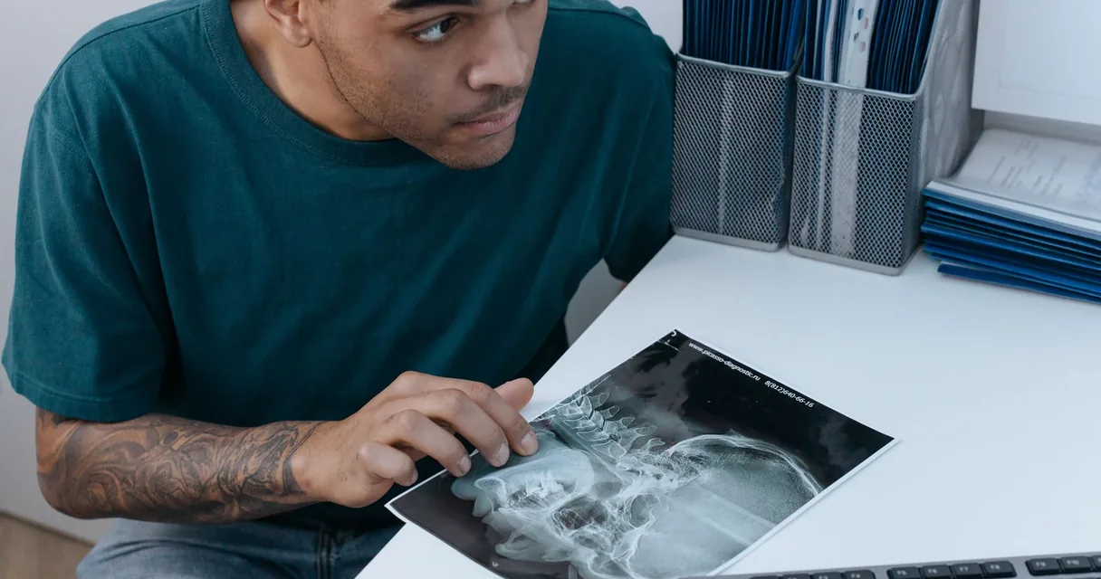 Homem examinando uma radiografia da bacia sobre a mesa